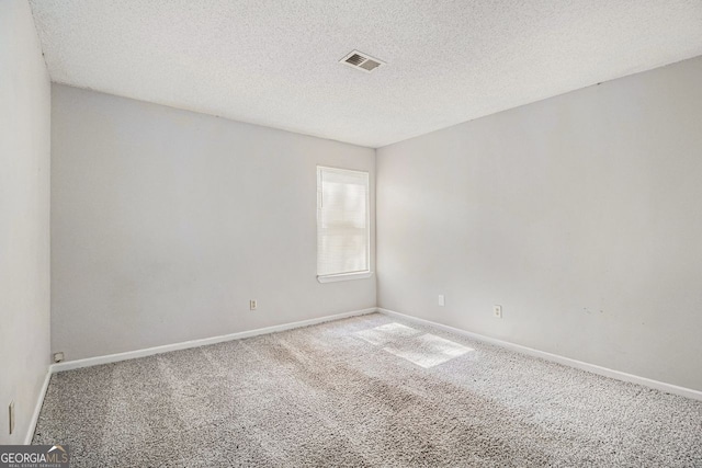 carpeted empty room with baseboards, visible vents, and a textured ceiling