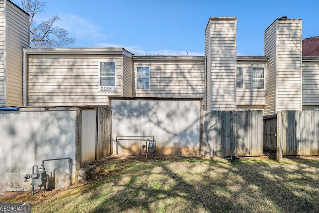 rear view of house featuring fence and a yard