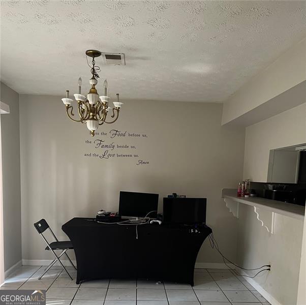 tiled dining room with a textured ceiling and a chandelier