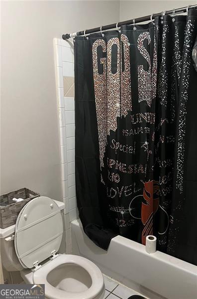 bathroom with tile patterned floors, toilet, and shower / bath combo with shower curtain