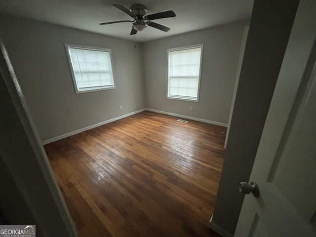 empty room with dark hardwood / wood-style flooring and ceiling fan