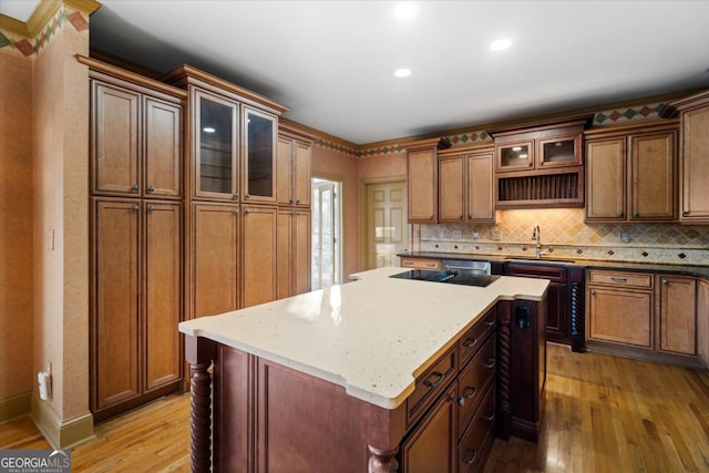 kitchen featuring light stone countertops, light hardwood / wood-style flooring, a kitchen island, and sink