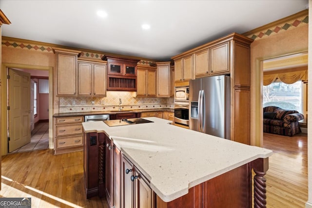 kitchen with decorative backsplash, light wood-type flooring, light stone counters, stainless steel appliances, and a center island