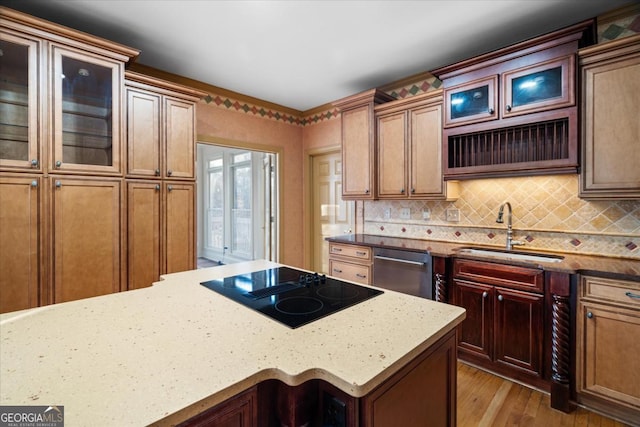 kitchen with sink, stainless steel dishwasher, light stone countertops, black electric cooktop, and light hardwood / wood-style floors