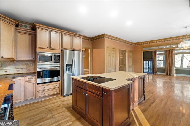 kitchen with pendant lighting, light wood-type flooring, stainless steel appliances, and light stone counters