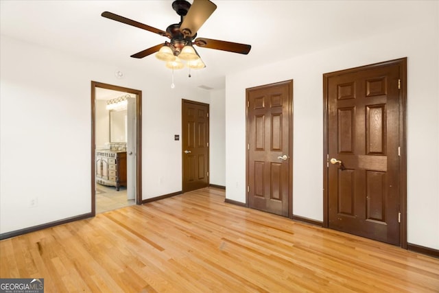 unfurnished bedroom featuring connected bathroom, light hardwood / wood-style floors, ceiling fan, and multiple closets