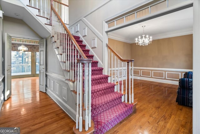 staircase featuring a notable chandelier, wood-type flooring, and crown molding