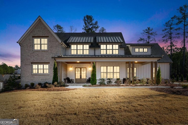 view of front facade featuring a porch, french doors, and a lawn