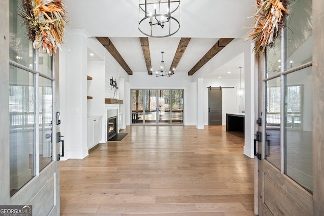 entrance foyer featuring beam ceiling, french doors, a barn door, a chandelier, and light wood-type flooring