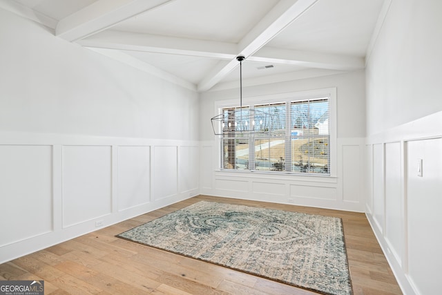 dining area featuring beamed ceiling, light wood-type flooring, and coffered ceiling