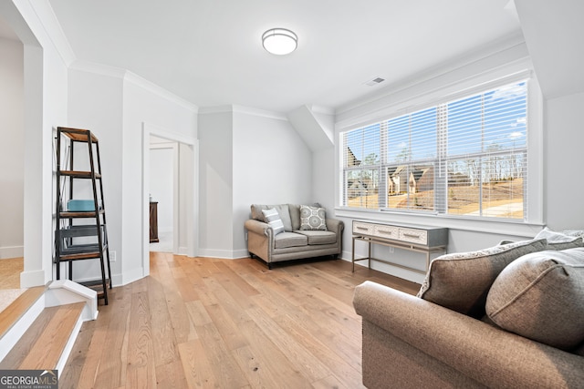 living area with light hardwood / wood-style floors and crown molding