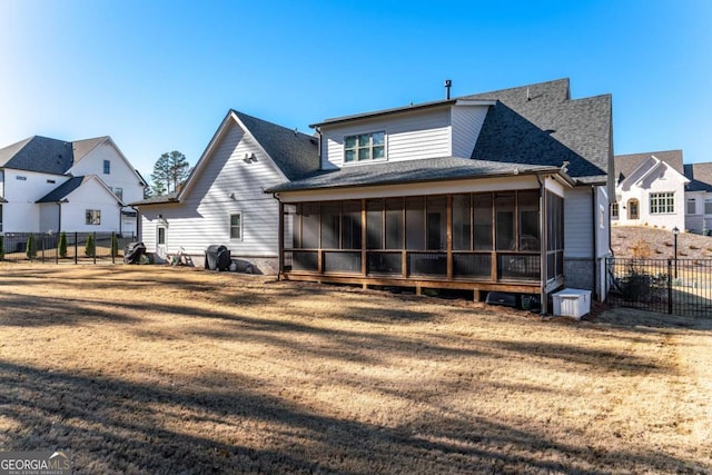 back of property with a sunroom and a lawn