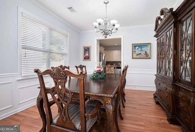 dining area featuring a chandelier, light hardwood / wood-style flooring, and ornamental molding