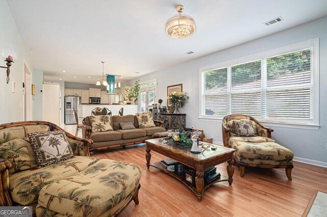 living room with light hardwood / wood-style floors and a notable chandelier