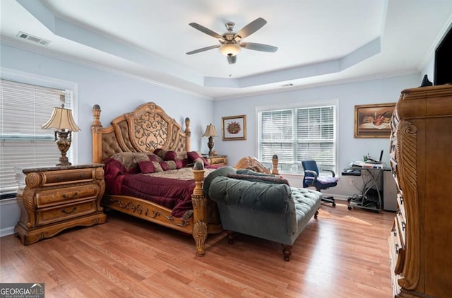 bedroom featuring light hardwood / wood-style floors, a raised ceiling, ceiling fan, and ornamental molding