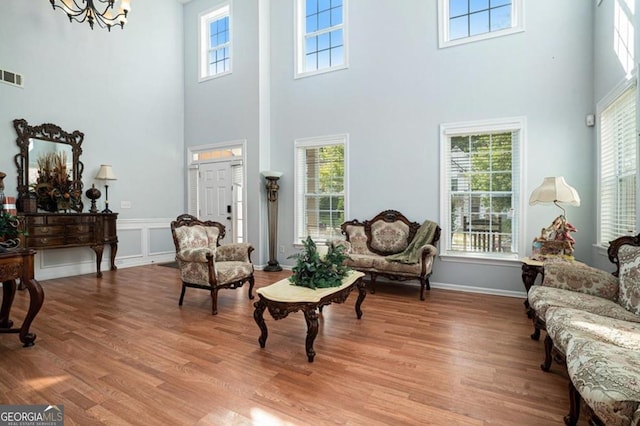 sitting room with a towering ceiling, a healthy amount of sunlight, and light wood-type flooring