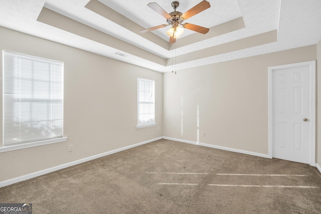 spare room with carpet flooring, ceiling fan, and a tray ceiling