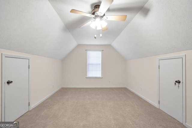 additional living space featuring a textured ceiling, ceiling fan, light colored carpet, and lofted ceiling