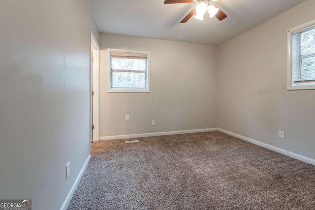 empty room with carpet flooring, ceiling fan, and a wealth of natural light