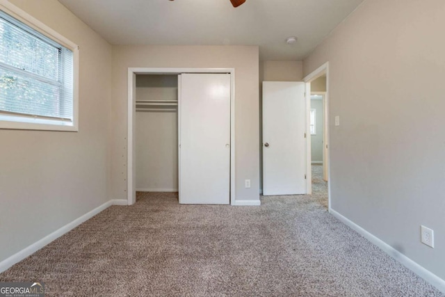 unfurnished bedroom with light carpet, a closet, and ceiling fan