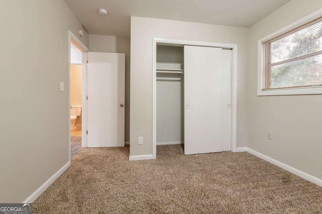 unfurnished bedroom with light carpet and a closet