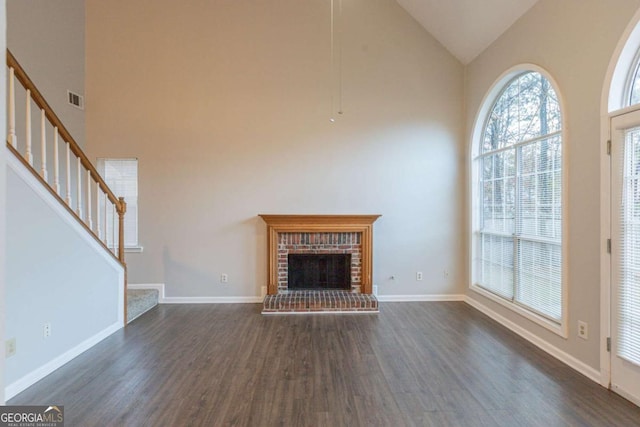 unfurnished living room with dark hardwood / wood-style flooring, high vaulted ceiling, and a brick fireplace