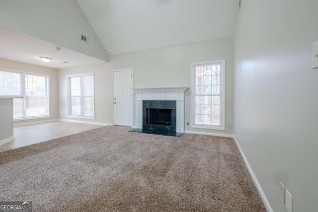 unfurnished living room featuring a fireplace, carpet floors, and high vaulted ceiling