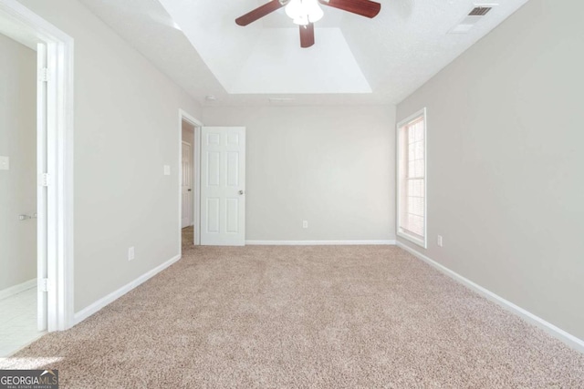 carpeted empty room featuring ceiling fan and a raised ceiling