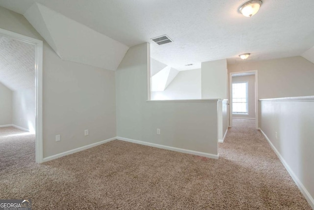 bonus room with a textured ceiling, light colored carpet, and lofted ceiling