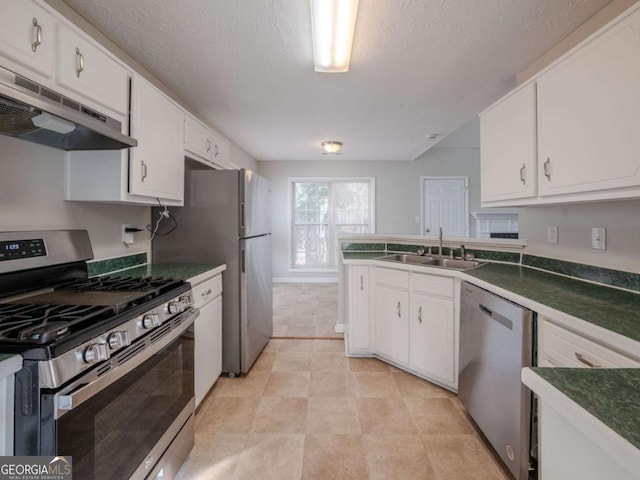 kitchen with a textured ceiling, stainless steel appliances, white cabinetry, and sink