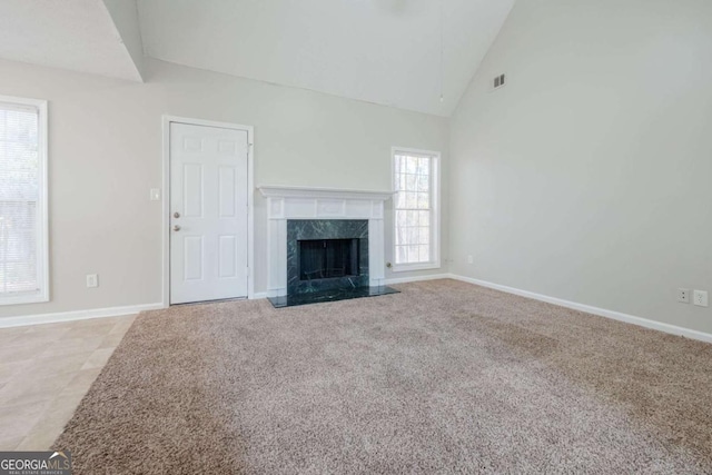 unfurnished living room featuring a fireplace, light colored carpet, high vaulted ceiling, and a healthy amount of sunlight