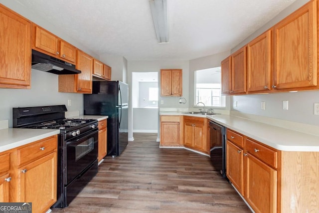 kitchen featuring black appliances, sink, dark wood-type flooring, and a textured ceiling