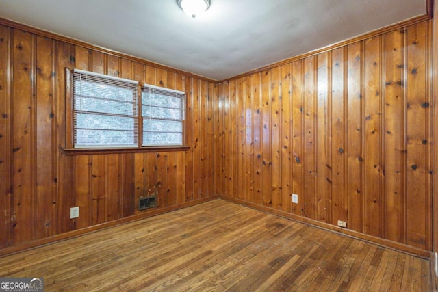 spare room featuring hardwood / wood-style floors and wood walls