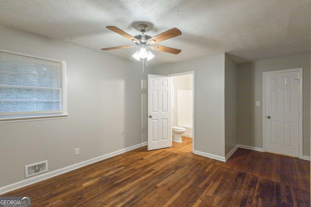 unfurnished bedroom with a textured ceiling, ceiling fan, dark wood-type flooring, and connected bathroom