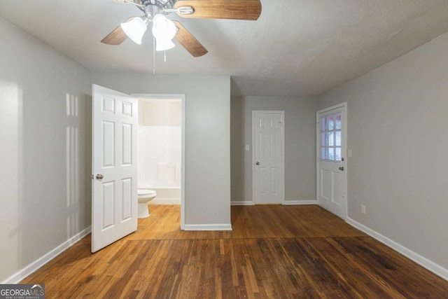 unfurnished bedroom featuring ensuite bath, ceiling fan, dark hardwood / wood-style flooring, and a textured ceiling