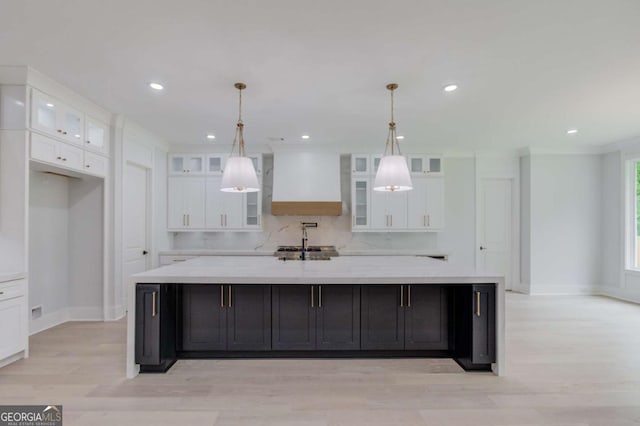 kitchen with custom range hood, backsplash, hanging light fixtures, and a large island