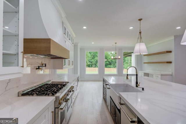 kitchen with light hardwood / wood-style flooring, custom range hood, light stone counters, white cabinetry, and stainless steel appliances