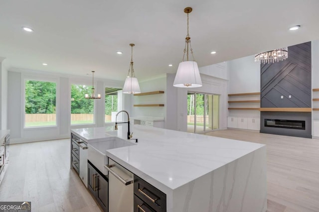 kitchen with a center island with sink, hanging light fixtures, stainless steel dishwasher, and sink