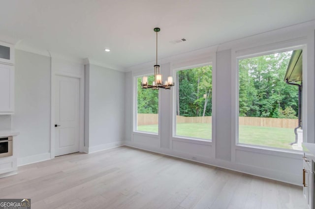 unfurnished dining area featuring light hardwood / wood-style floors, crown molding, and a notable chandelier