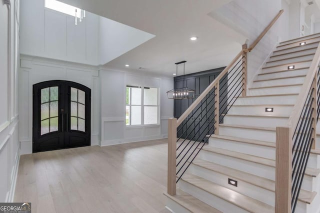 foyer featuring a notable chandelier, light wood-type flooring, and french doors