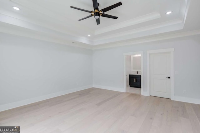 unfurnished living room with a tray ceiling, ceiling fan, light hardwood / wood-style flooring, and ornamental molding