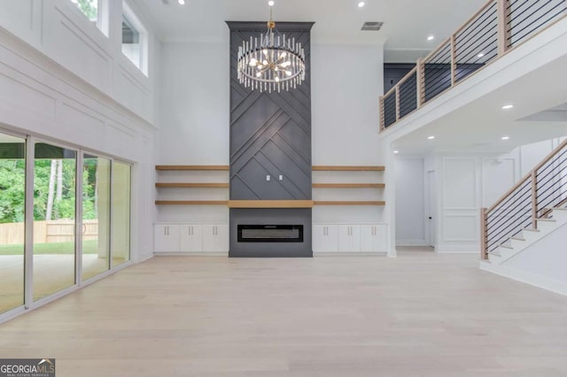 2626 Sardis Way, Buford, GA 30519 - unfurnished living room with a high ceiling, stairway, a chandelier, light wood-style flooring, and a fireplace