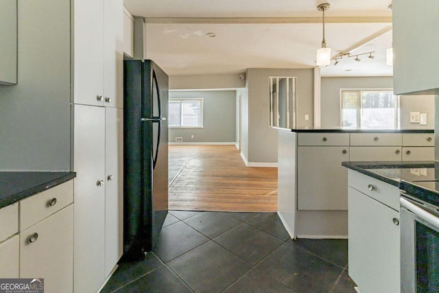 kitchen featuring dark hardwood / wood-style flooring, black fridge, stainless steel range with electric stovetop, decorative light fixtures, and white cabinetry