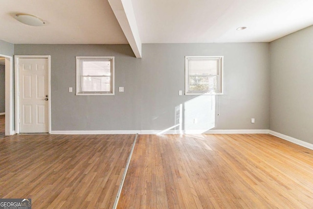 unfurnished living room featuring hardwood / wood-style floors, plenty of natural light, and beamed ceiling