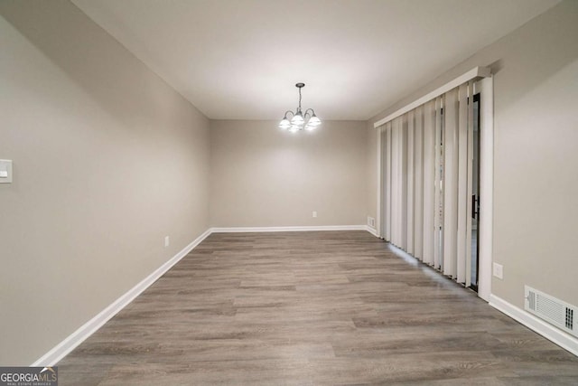 unfurnished dining area featuring hardwood / wood-style flooring and an inviting chandelier