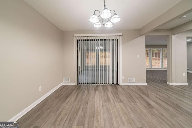 empty room with an inviting chandelier and hardwood / wood-style flooring