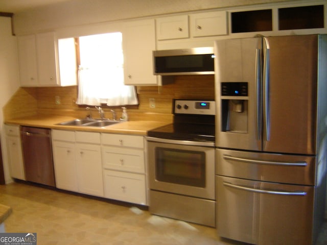 kitchen with decorative backsplash, white cabinetry, sink, and appliances with stainless steel finishes