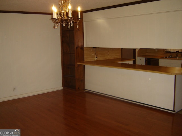 empty room featuring sink, crown molding, dark hardwood / wood-style floors, a textured ceiling, and a notable chandelier