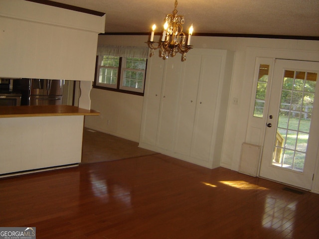 unfurnished dining area featuring dark hardwood / wood-style floors, crown molding, plenty of natural light, and a notable chandelier