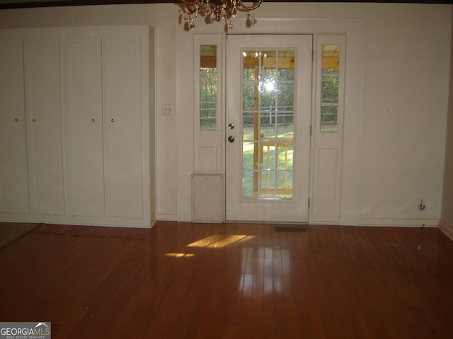 doorway to outside featuring wood-type flooring and a notable chandelier